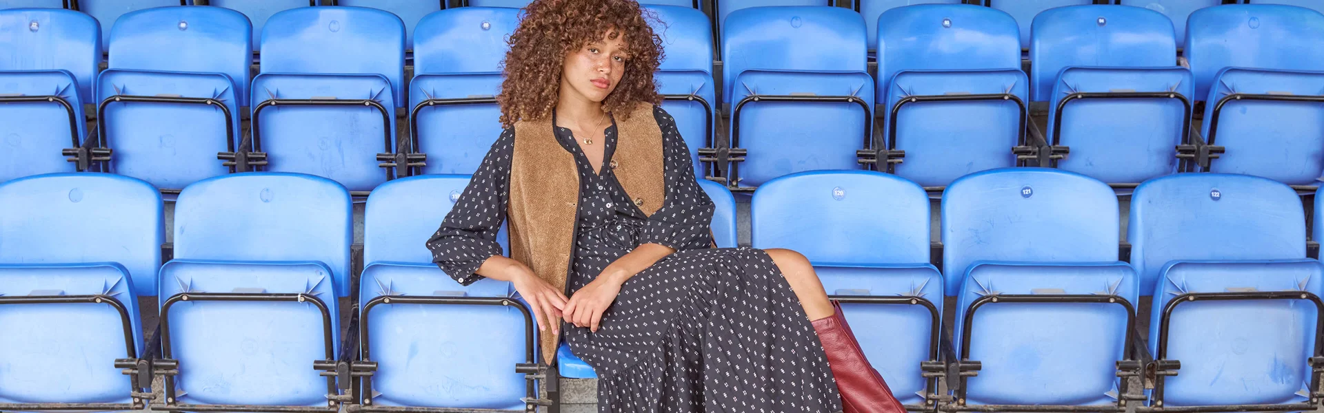 Femme sur des chaises bleues dans une robe à pois noirs
