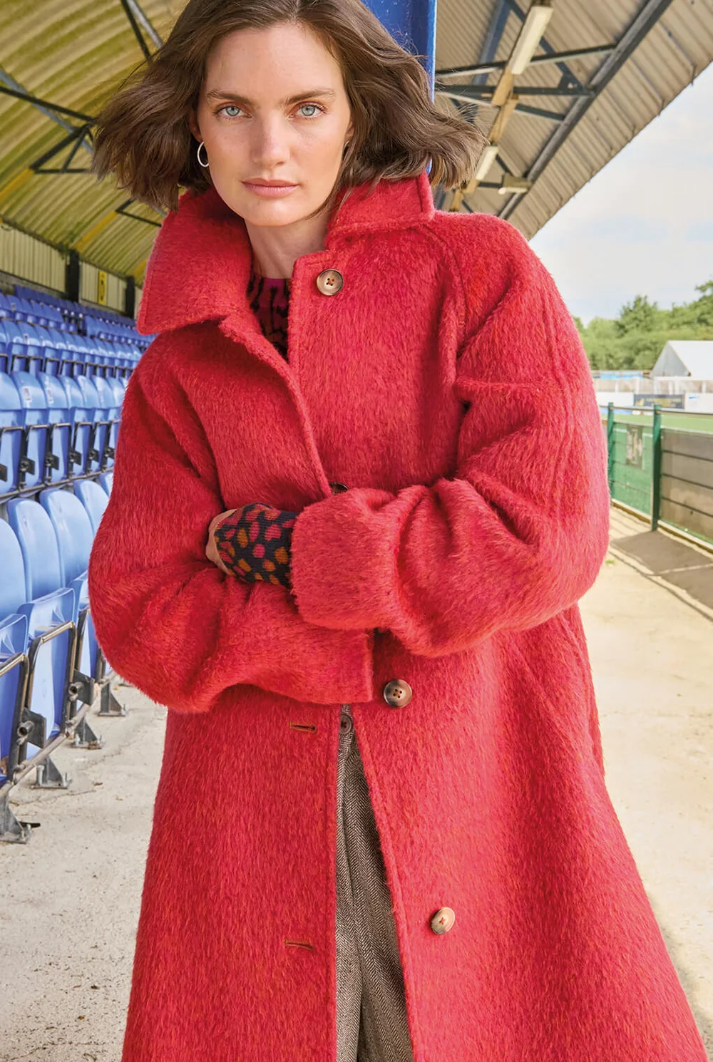 Femme aux bras croisés dans un manteau rouge vif